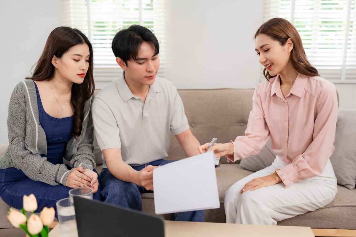 A professional financial advisor meeting with clients at home to review important documents
